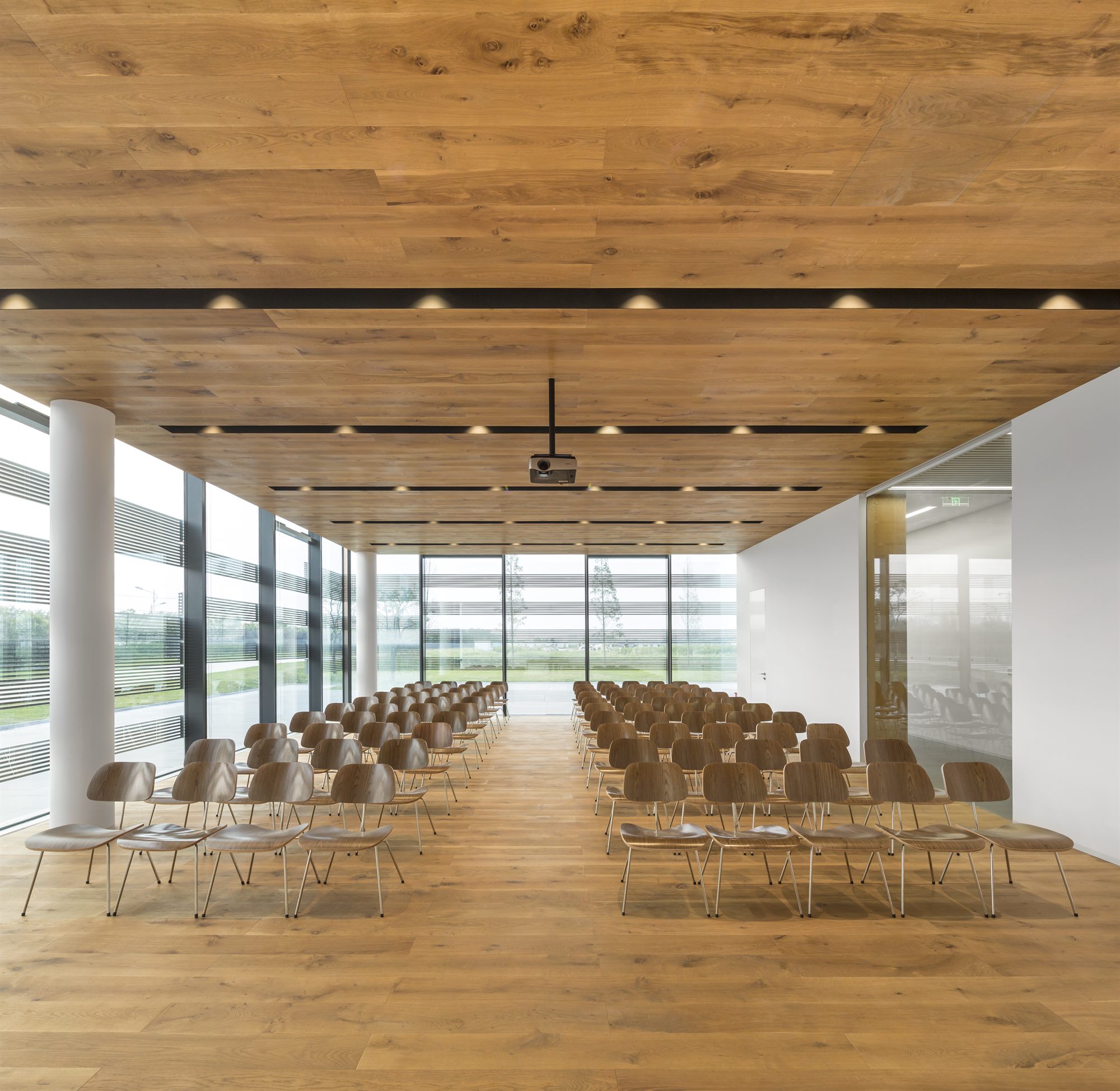 Timber-ceilinged lecture hall with rows of chairs and glazed walls, Donghai office building