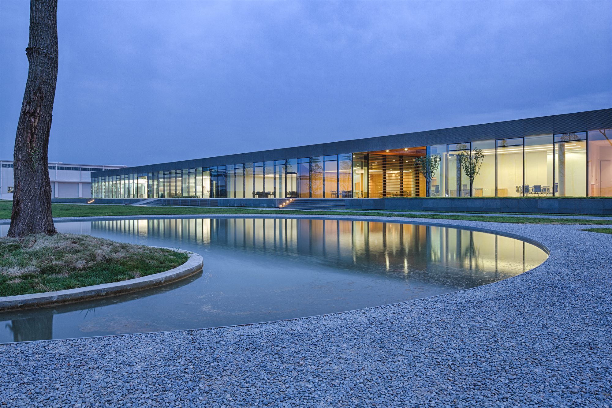 Donghai office building at dusk, reflected in a curved pond