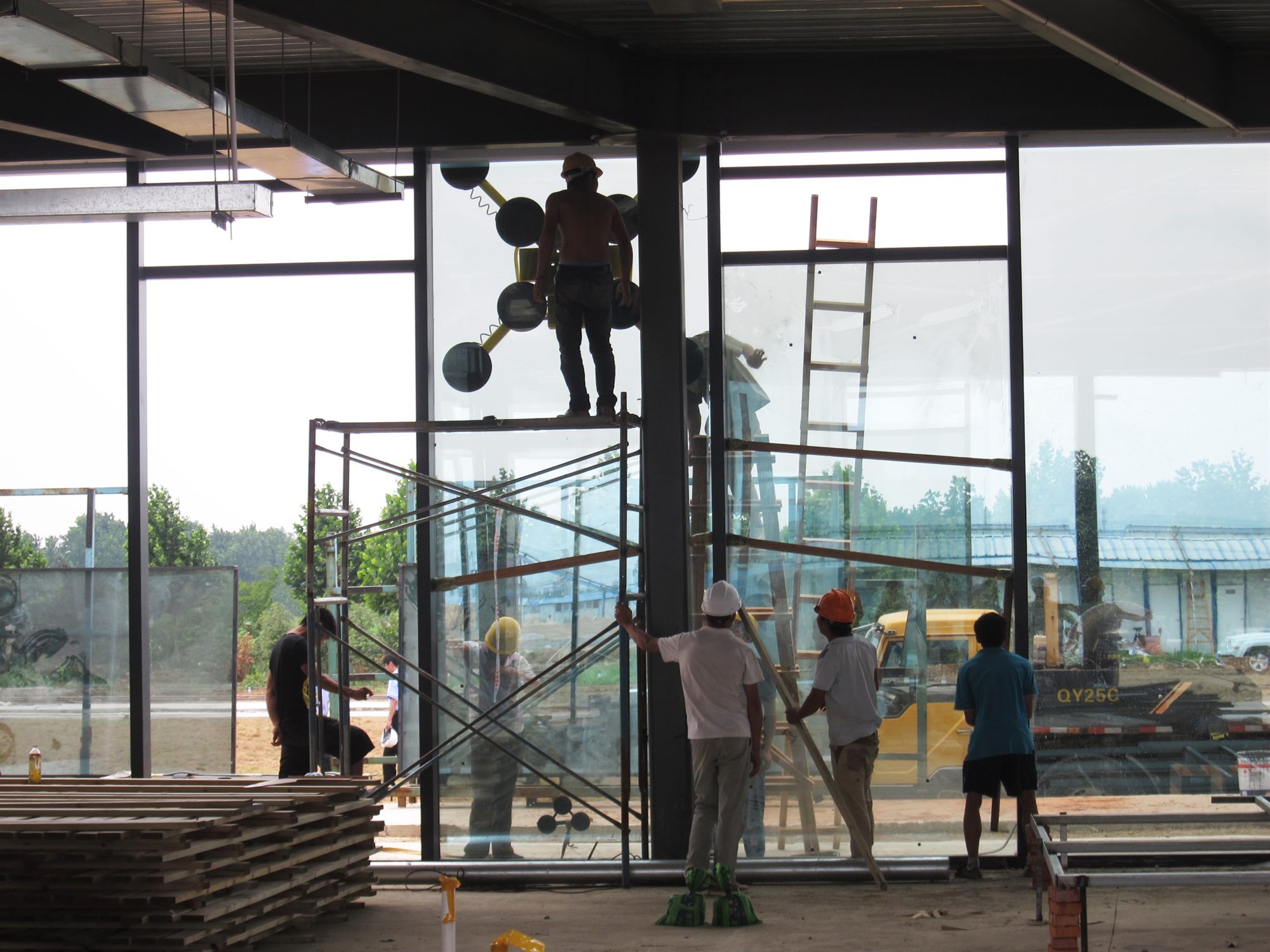 Workers installing large (5.4 m × 1.8 m) glass panels during construction of the Donghai office building
