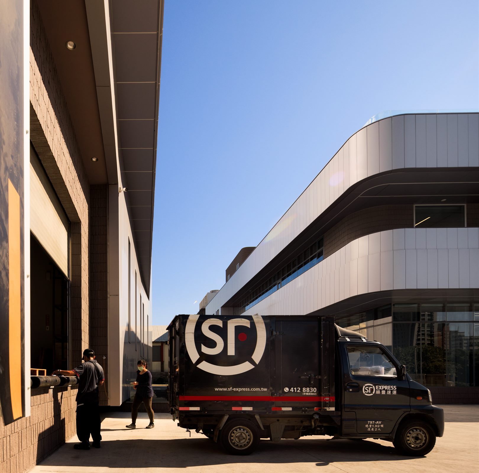 Delivery van at the loading area beneath the curved façade of the Quest Composite factory building