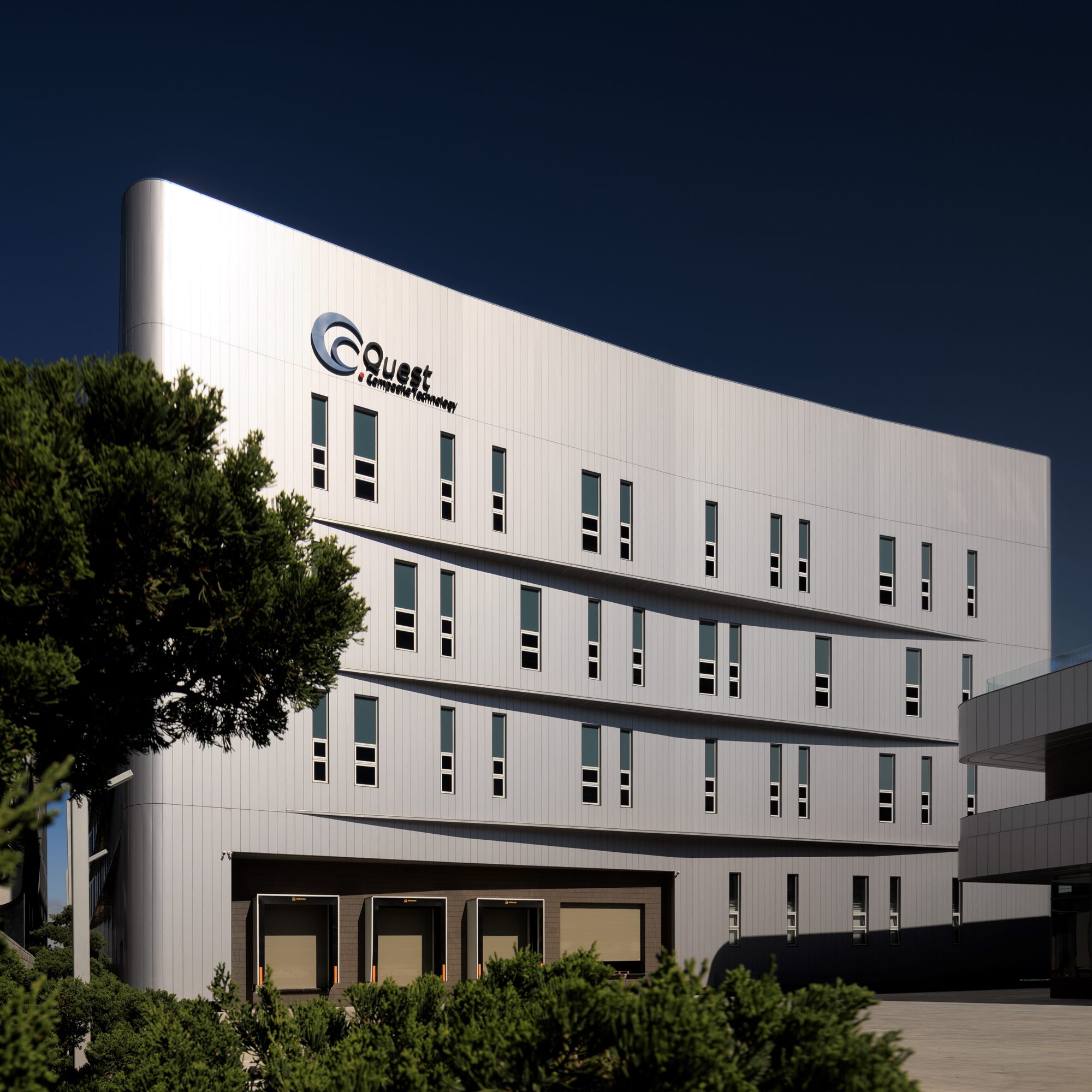Curved metallic façade of the Quest Composite factory building with the company logo, Taichung