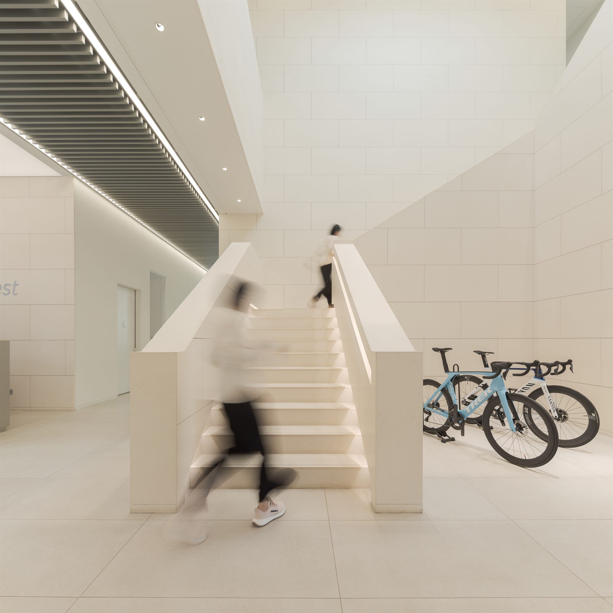 Sculptural white staircase with bicycles on display, Quest Composite office