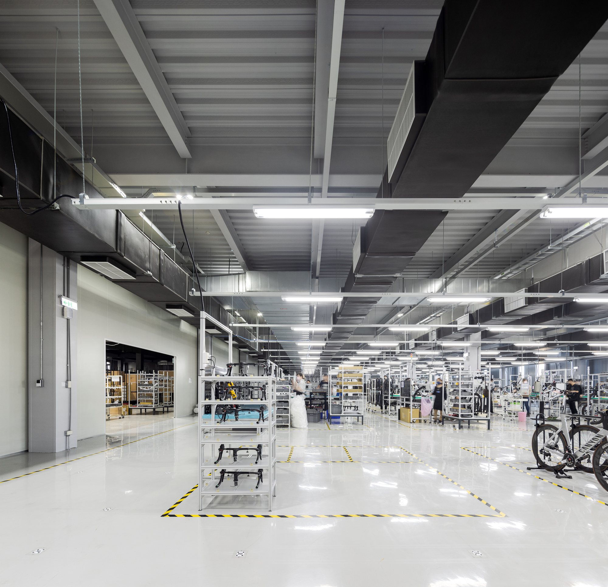 Bright production hall with workers and AGVs working side by side, Quest Composite factory