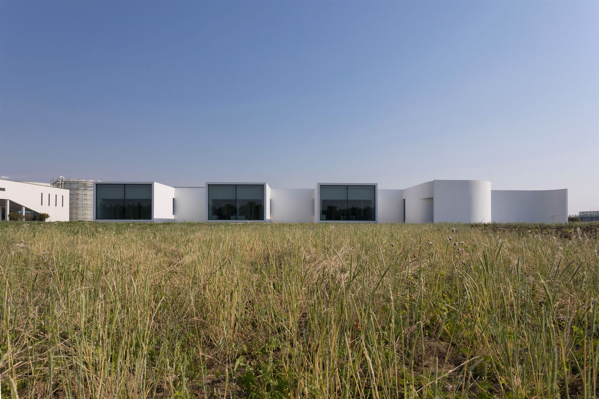Salt laboratory's white buildings low on the horizon beyond grassland, Huai'an
