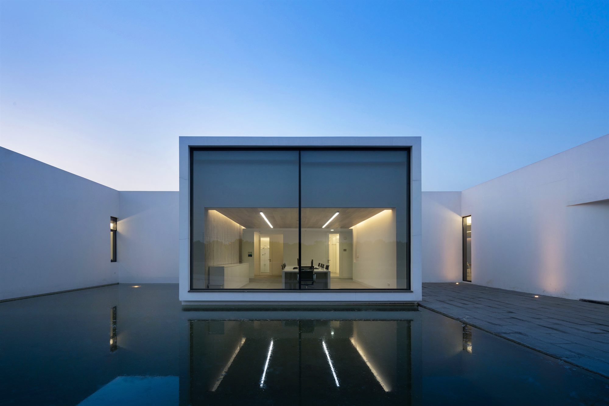 Glazed courtyard window of the salt laboratory reflected in a water pool at dusk