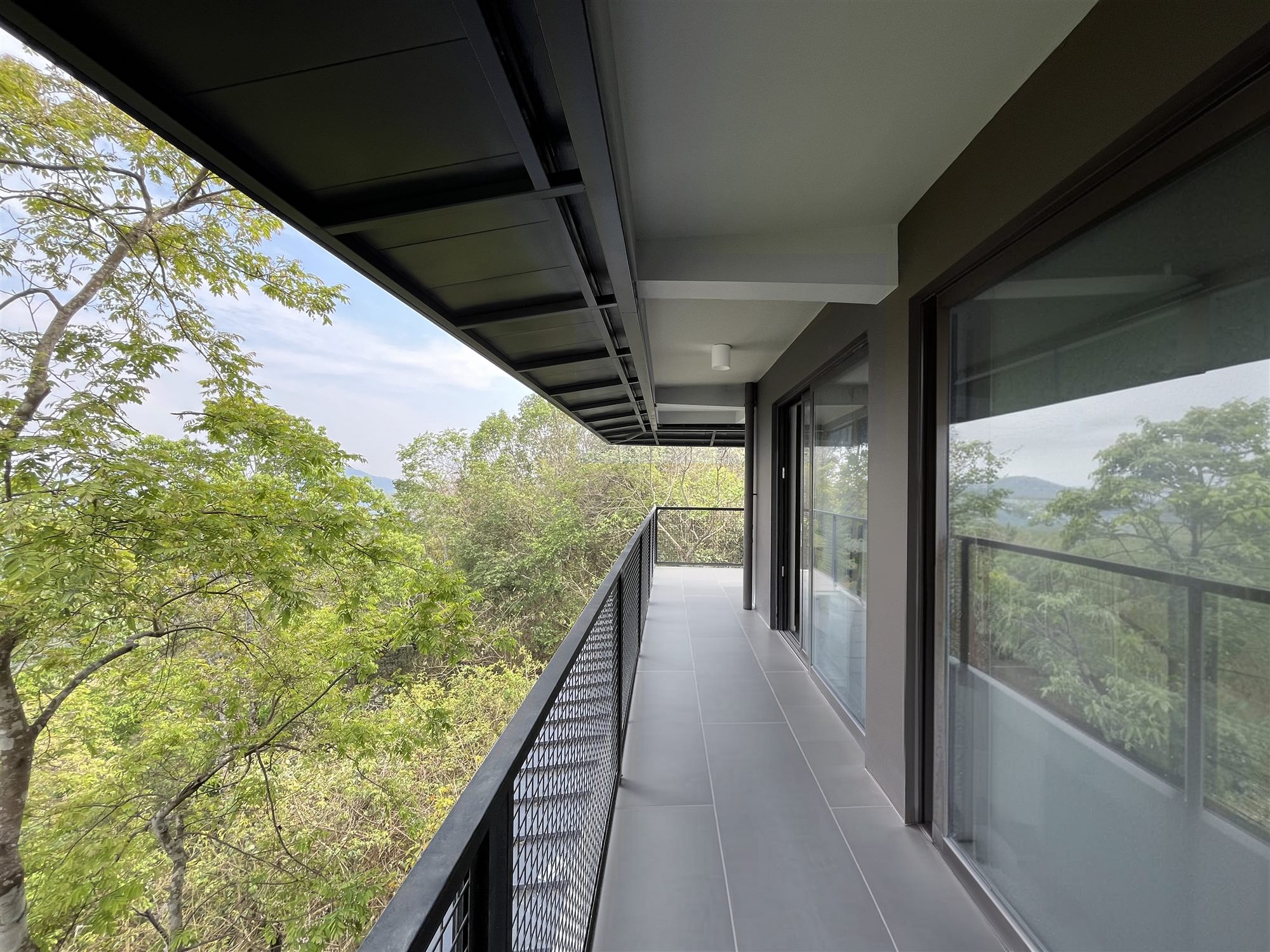 Covered terrace of the dormitory with deep roof overhang looking over the forest, Shan Tea factory