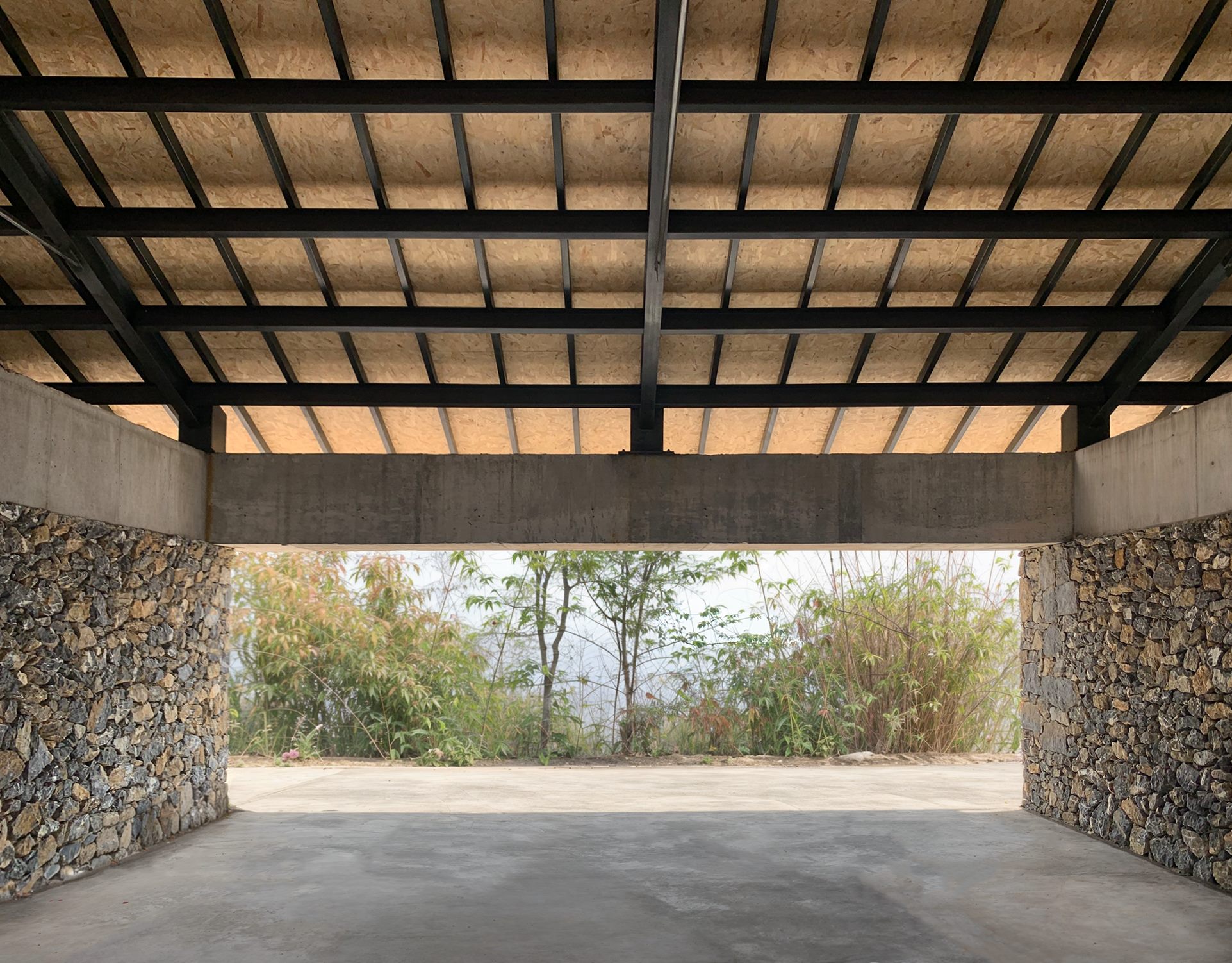Entrance of the dining building, with stone walls and timber roof framing the forest, Shan Tea factory