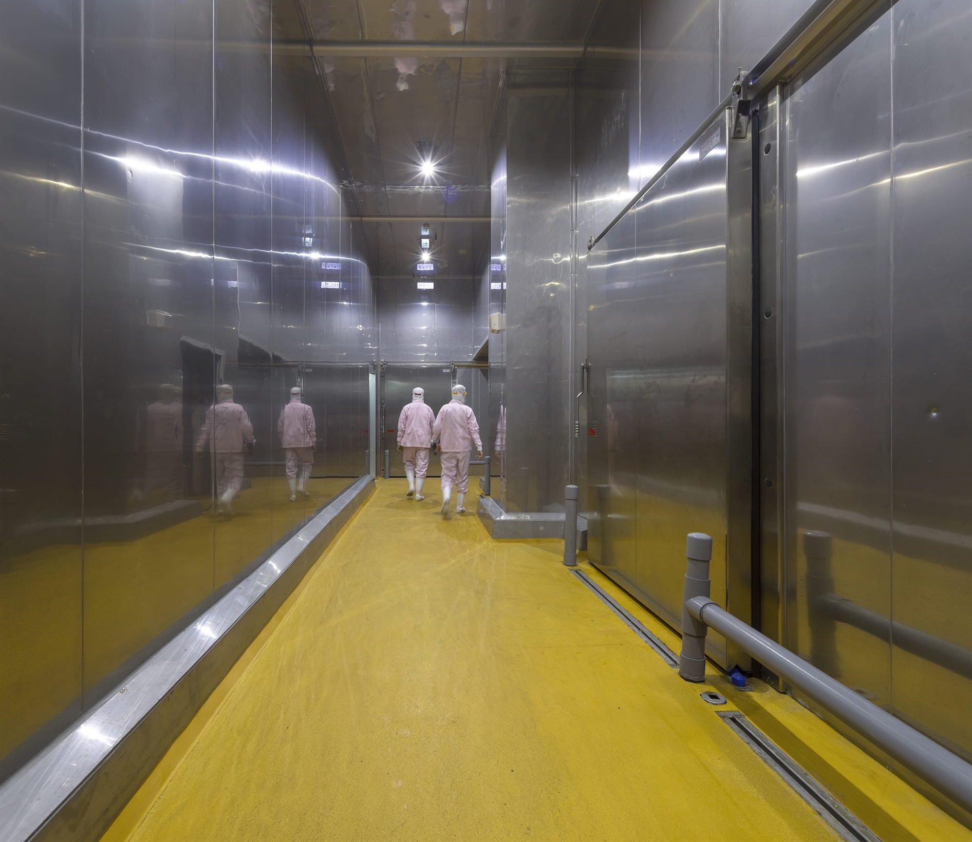 Hygienic production corridor with stainless-steel walls and yellow floor, T-HAM factory