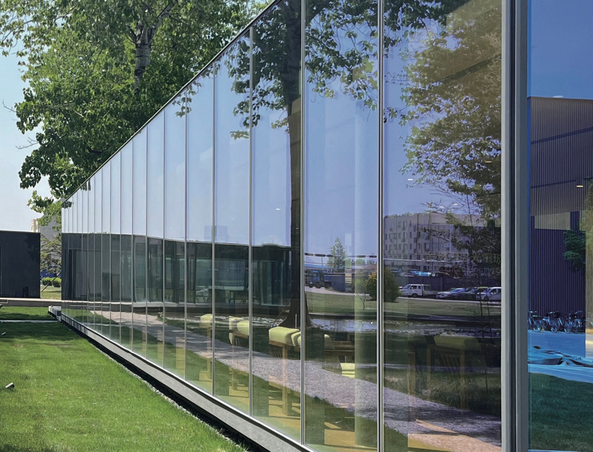 Colour-shifting glass curtain wall of the showroom among trees, Qingdao