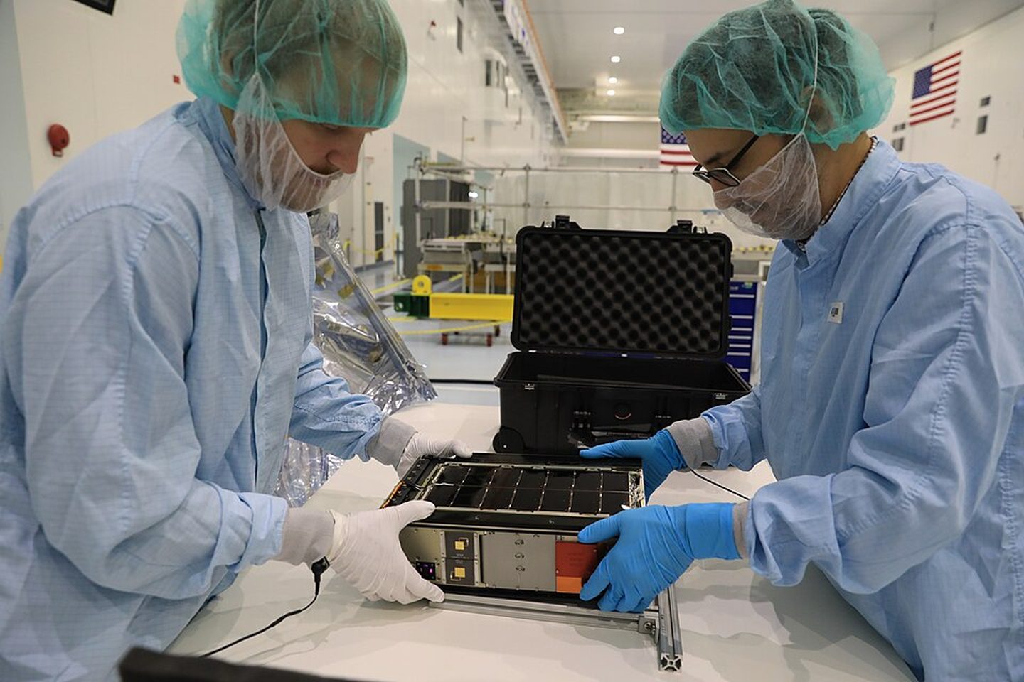 Technicians in cleanroom gowns handling equipment
